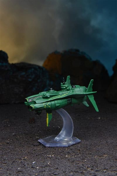 A green toy spaceship with yellow details is displayed on a clear stand against a dramatic backdrop of dark clouds and rocks, evoking a sci-fi theme reminiscent of Starfinder adventures from Paizo's Starship Minis collection.