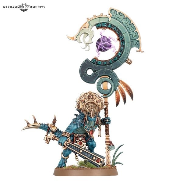 A Games Workshop miniature, the Saurus Astrolith Bearer from Age of Sigmar, wields a large ornate staff crowned with a glowing purple orb. Its intricate armor includes a headdress and serrated weapon. The base is adorned with small grass tufts, adding to its colorful and detailed design.