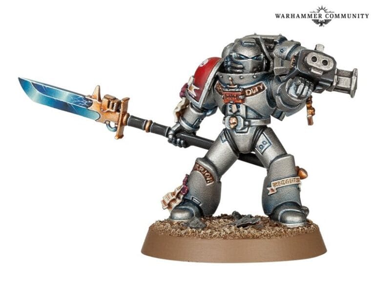 A detailed Grey Knight Miniature from Games Workshop stands proudly on a textured base. The silver armor gleams, while the warrior holds a majestic blue and gold sword in one hand and a gun in the other, showcasing intricate detailing. It's truly a standout mini of the month.