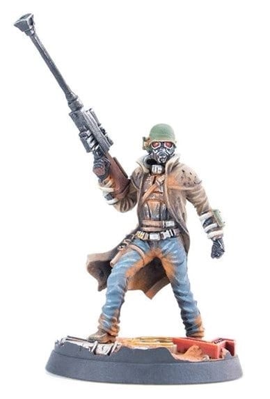 A figurine of a soldier in a long coat and helmet, reminiscent of a Fallout NCR Ranger, holds a large rifle pointed upward. The soldier stands on a detailed base, wearing a gas mask and rugged clothing crafted for Wasteland Warfare.