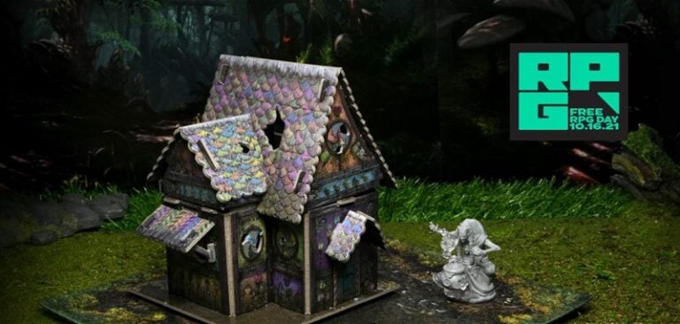 A miniature model of a fantasy house, reminiscent of a Grim Cottage Encounter, boasts colorful shingles and detailed walls against a dark forest background. Beside it stands a small figurine. A graphic reads "WizKids Free RPG Day 10.16.21" in the top right corner.