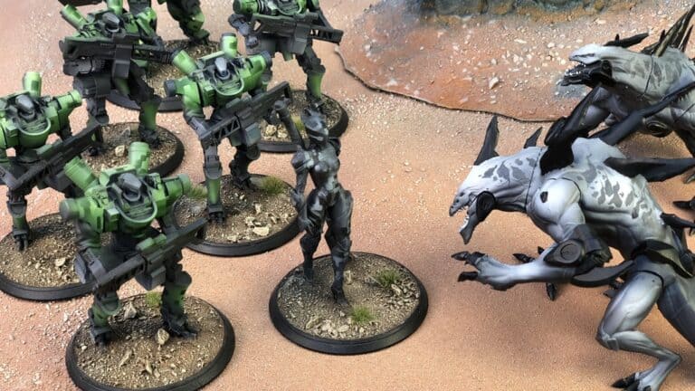 A tabletop game scene unfolds with green-armored soldiers and a female warrior from "Immortal Kings" facing off against monstrous creatures. The captivating desert landscape with rocky formations sets the stage for this dramatic miniatures game, reminiscent of a Kickstarter campaign sensation.