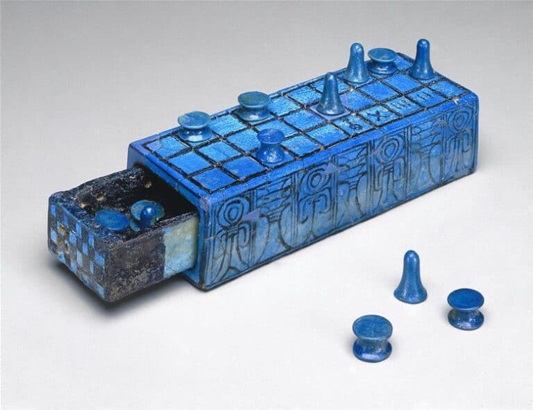 A blue ancient board game set with a rectangular grid, ornate patterns, and various pieces shaped like small cones and discs. Some pieces are placed on the board, others arranged beside it. Echoing the rich tapestry of board games history, the box features a pull-out drawer.