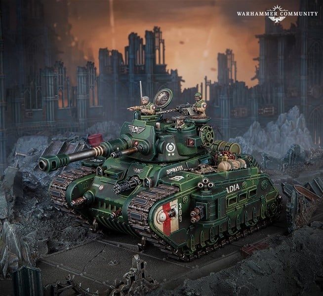 A detailed miniature model of a green Rogal Dorn Tank with weapons and insignias, set in a diorama of a ruined, post-apocalyptic urban landscape. The scene evokes the craftsmanship of Games Workshop, featuring dilapidated buildings and debris for an immersive preview.