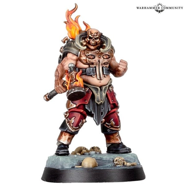 A detailed miniature figure of Skullgrinder Herax, a muscular warrior with flaming hair, wearing spiked armor and holding a flaming mace. Skulls and bones lie at his feet on a textured base. "Warhammer Community" and "Games Workshop" are proudly displayed in the top right corner.