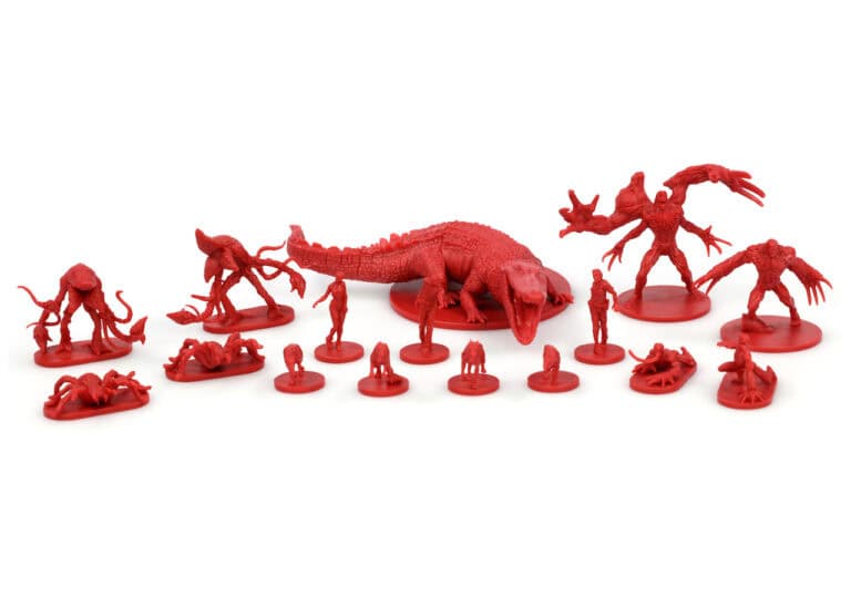 A collection of small, detailed red plastic miniatures from Steamforged depicts various monstrous creatures and figures, including a large crocodile-like beast reminiscent of Resident Evil's eerie world. They are meticulously arranged in a line on a white surface.