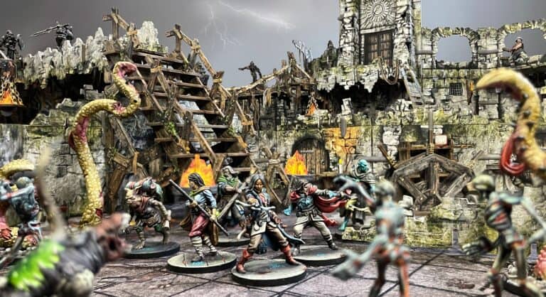 In the Dungeons of Enveron, a group of detailed fantasy miniatures in battle poses stands amidst a ruined, castle-like backdrop. Flames and storm clouds set a dramatic scene, with lightning striking in the distance. Monsters and adventurers clash in this intricate tabletop setup powered by Kickstarter funding.