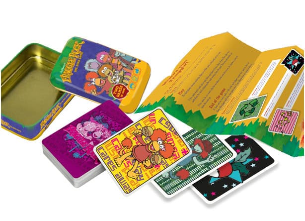 Pre-order the vibrant Fraggle Rock card game by River Horse, complete with a tin storage box. The open box showcases colorful character illustrations and detailed instructions, offering a delightful glimpse into this whimsical world.