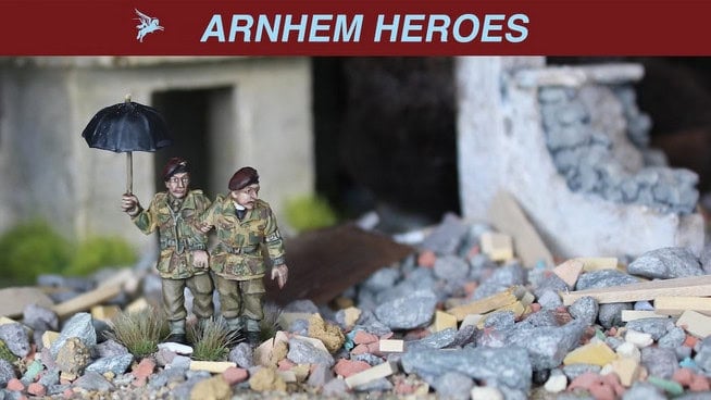 Two miniature soldiers in camouflage uniforms stand amidst rubble, embodying the valor of British Airborne Troops. One holds an umbrella against a backdrop of a partially destroyed building. The scene is aptly titled "ARNHEM HEROES 1944," adorned with a winged insignia.
