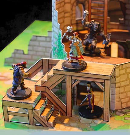Miniature figures set in a fantasy setting evoke the charm of tabletop RPGs with detailed terrain. A knight, a mage, and a large creature stand on a wooden platform inside a stone building, surrounded by Dungeons Pop-inspired colorful, textured backdrops.