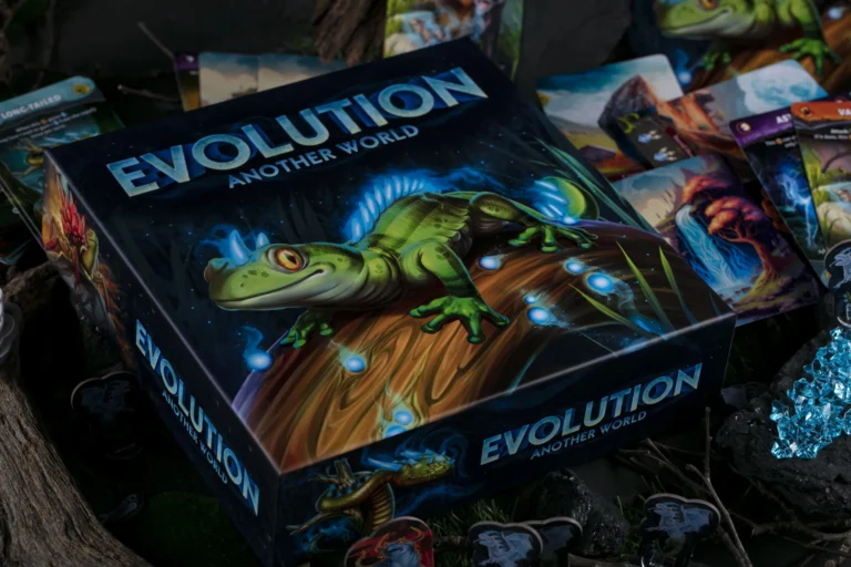 A board game box titled "Evolution: Another World" from CrowD Games features an illustrated green lizard on a vibrant, glowing landscape. Surrounding the Kickstarter-backed box are various cards and game pieces, set against a dark, natural backdrop.