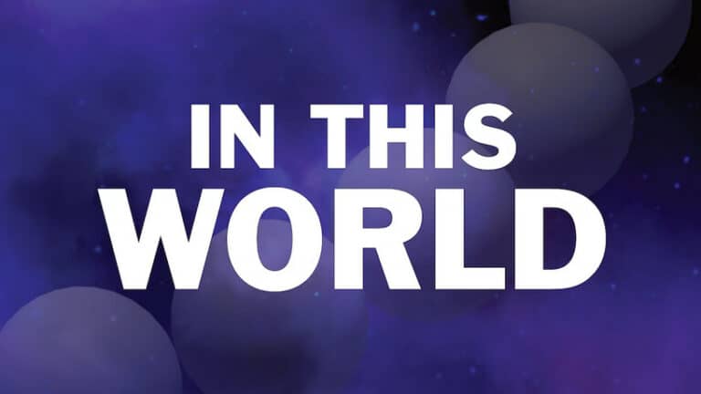 The image features the words "IN THIS WORLD" in bold white letters against a background of deep blue and purple hues, with circular gradients resembling planets or celestial bodies, reminiscent of a cosmic Kickstarter game exploring the universe through a microscope lens.