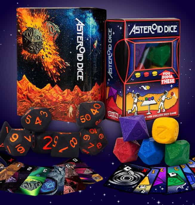 A collection of Asteroid Dice featuring orange numbers and an outer space theme. The box art depicts an asteroid crashing on a mountain landscape. Various shaped dice and game cards are displayed alongside the boxes, making it a perfect addition to your Kickstarter-funded dice games.
