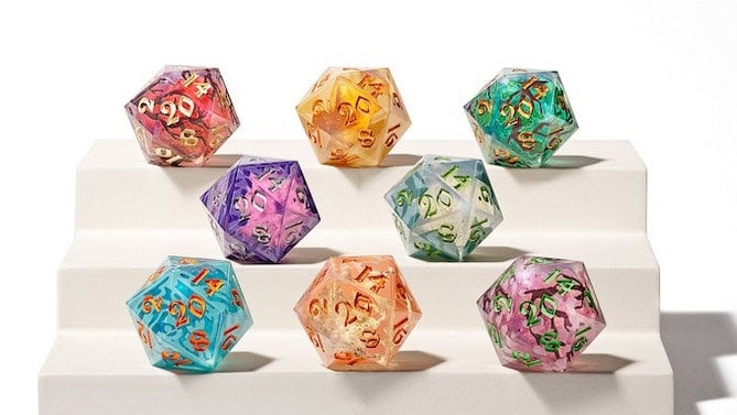 A set of seven colorful, resin-filled Wild Earth Dice displayed on white stair-like platforms. Each die contains vibrant hues and embedded textures with gold numbers visible on their surfaces, making them a perfect Kickstarter find for any dice enthusiast.