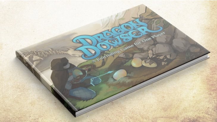 A hardcover book titled "Dragon Dowser: A Journaling Game for One Player" features a solarpunk RPG aesthetic with an illustration of a figure crouched by rocks, encountering dragon eggs. The cover's parchment-like background adds to its Kickstarter charm.