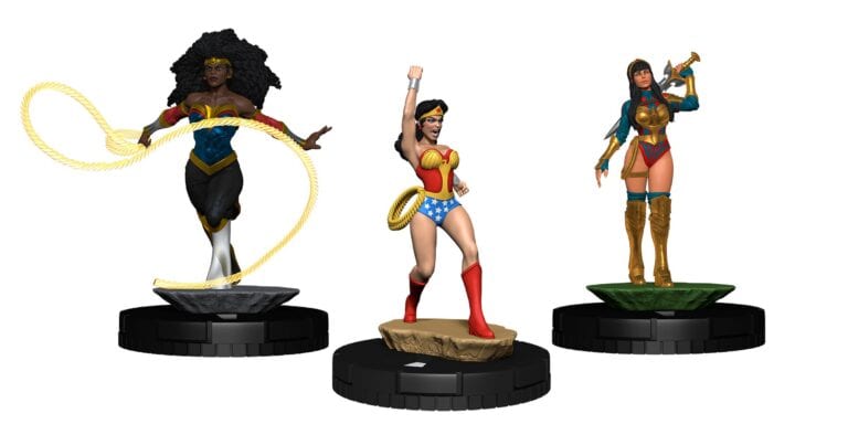 Three HeroClix superhero figurines stand on circular bases. The first on the left has curly hair and a golden lasso. The middle one lifts her arm with a similar lasso. The one on the right holds a golden trumpet, wearing red and blue armor—all part of the 2023 Summer Convention Exclusives at San Diego Comic-Con.