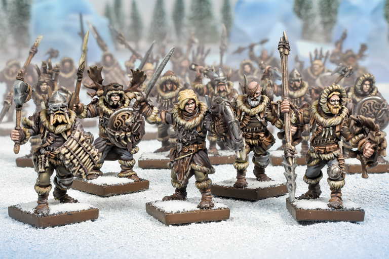 A group of intricately painted Northern Alliance Units from Mantic Games, resembling warriors in fur-lined armor, hold weapons. They are arranged on a snowy battlefield with a blurred forest background, creating a dynamic scene.