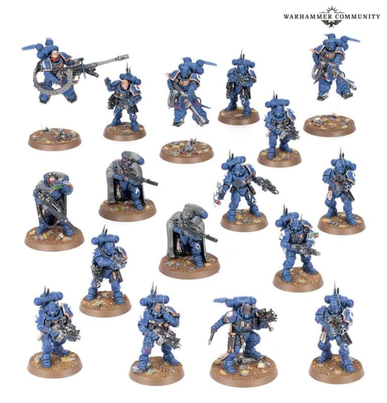 Miniature blue armored Space Marines with various weapons and poses, arranged on small round bases. The models feature intricate details and are positioned on a white background, ready for an epic Kill Team showdown.