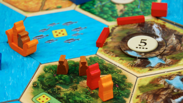 Close-up of the classic CATAN board game featuring hexagonal tiles with diverse terrains. Small wooden pieces represent roads, settlements, and cities on tiles depicting forests, fields, mountains, and water with fish.