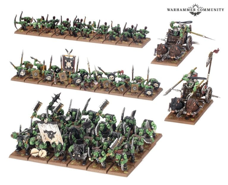 Several groups of painted miniature orc and goblin warriors are arranged in four rows. The figures feature green skin, various weapons, and armor, displayed on textured bases. An imposing chariot with orc riders is also included in the arrangement.