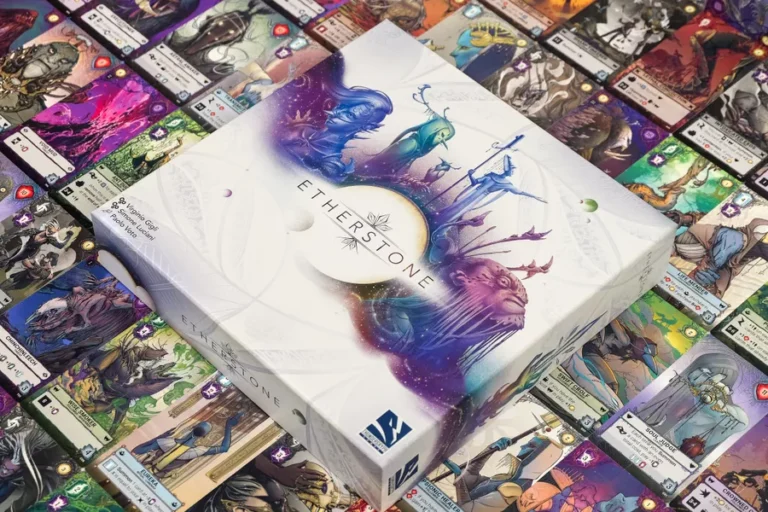 A box of "Etherstone" is centered on a table surrounded by colorful card illustrations, showcasing its Kickstarter origins. The box features a fantasy-themed design with ethereal creatures and landscapes, while the cards display various characters and vibrant artwork from this captivating card game.