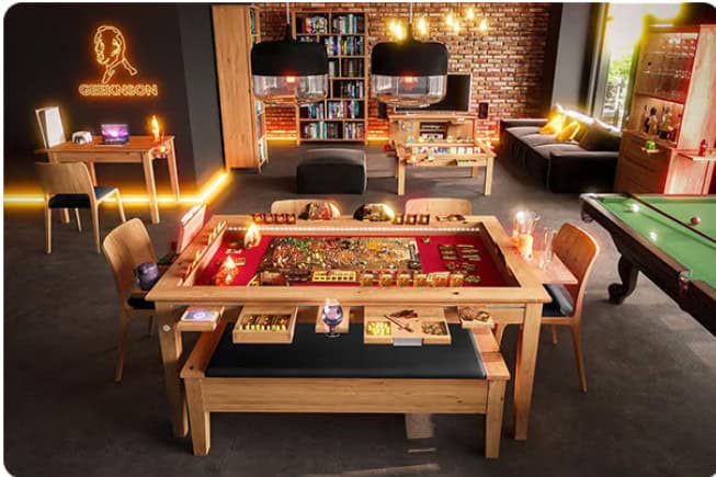 A cozy game room with a large wooden Geeknson table set up for board games, surrounded by chairs. A neon sign and bookshelves are visible in the background. The room is warmly lit with pendant lights and features a pool table on one side, creating the perfect Kickstarter-ready space.