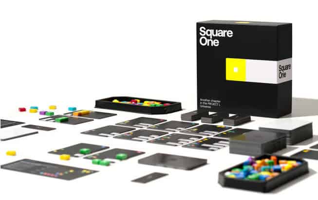 A modern board game titled "Square One" is showcased, reflecting its Kickstarter origins. The set includes colorful tokens, black game cards, and a sleek black box with a minimalist design featuring a yellow square and white text, reminiscent of Project L's contemporary aesthetics.