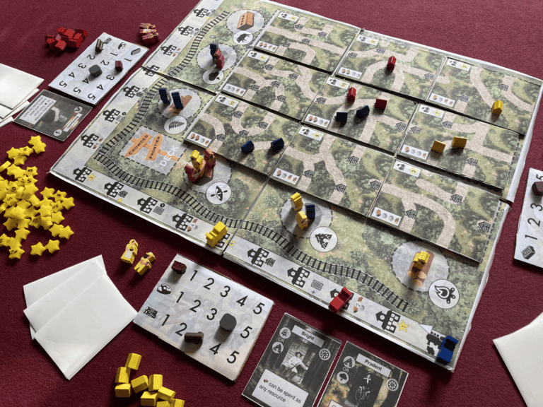 A board game setup with a grid of tiles, small colorful pieces, and cards sprawled across a table with a red tablecloth. Yellow star-shaped tokens and paper envelopes sit on the side. Some tiles illustrate railway tracks from Unpublished Board Game Designs' latest collection.
