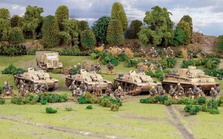 A diorama depicting a Bolt Action military scene with soldiers and tanks in a grassy field. Trees and bushes form a backdrop, and a military truck is visible behind the tanks. The Armies of Germany soldiers are positioned in various action poses.