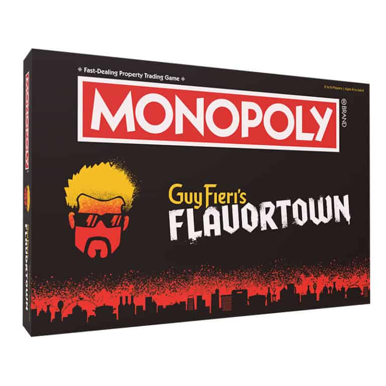 Cover of "MONOPOLY: Guy Fieri's Flavortown" board game. The design features a bold red-styled cityscape resembling a culinary trip, with an illustrated silhouette of someone with spiky hair and sunglasses. The background is predominantly black with red and white text.
