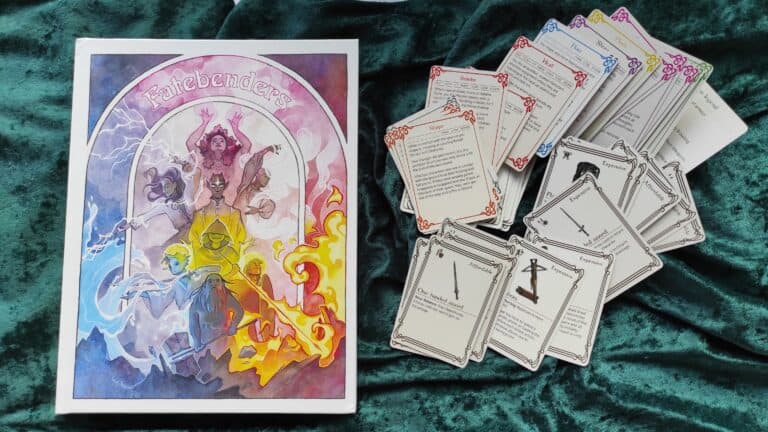 Board game box with colorful character art labeled "Fatebender" next to a pile of RPG game cards featuring various illustrations and text descriptions. The image is set on a green velvet surface, inviting you into a captivating fantasy adventure.
