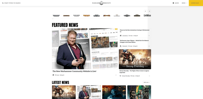 Screenshot of the redesigned Warhammer Community website showcasing featured news. A person stands holding a book in front of a display of Warhammer content. The page includes images and headlines about exciting new launches and game announcements.
